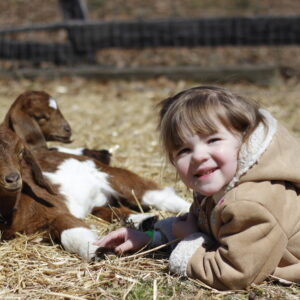 photo Kids Smiling in the Sun - Taken in the big goat pen with the baby goats at the  Easter Egg Hunt on  March 24, 2018 by Megan Somersall